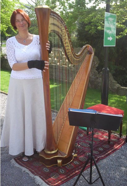 Marie France playing harp outdoors