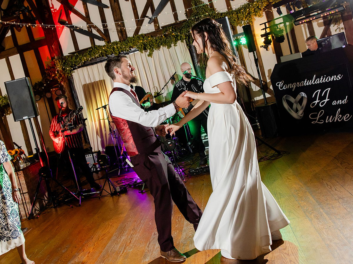Bride and groom dancing on their wedding day with a live wedding band and a DJ in the background