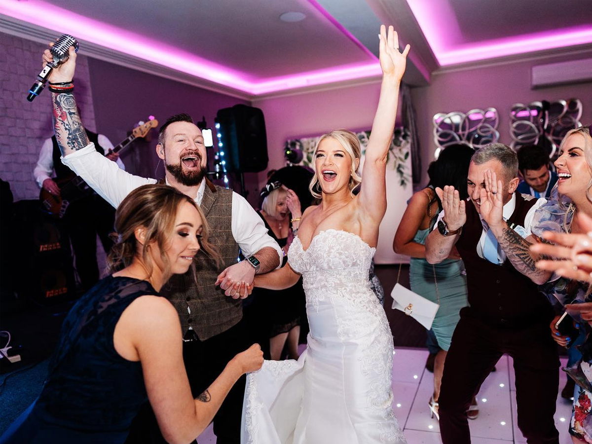 Wedding band singer on the dancefloor with dancing bride and guests